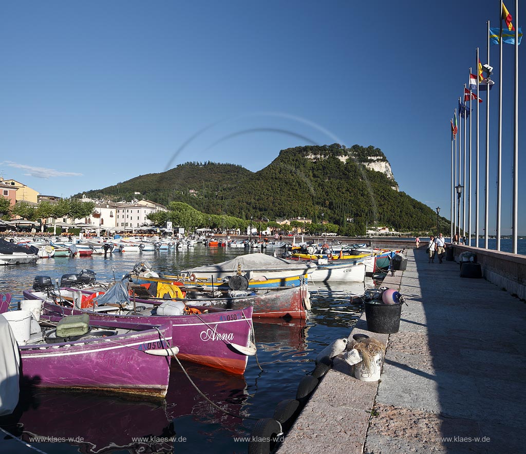 Garda Blick von der Hafenmole ueber Hafen mit bunten Fischerbooten,  Palazzo dei Capitani und Rocca di Garda im Hintergrund; Garda view from mole over port with colourful fishing boats, Palazzo dei Capitani and mountain Rocca di Garda in backgound