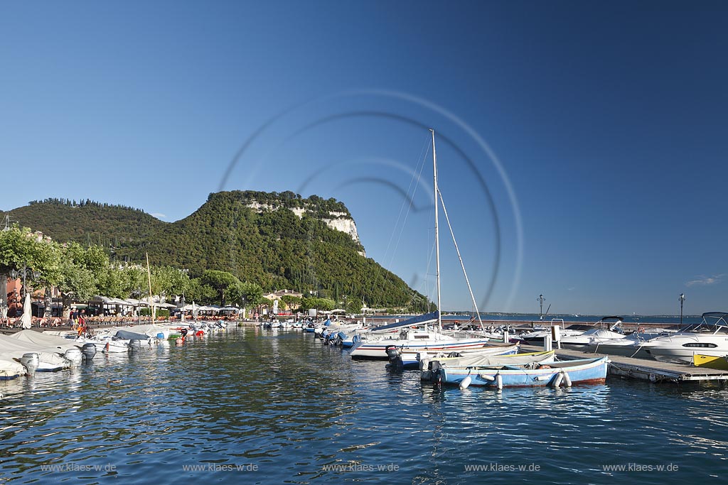 Garda Blick ueber Hafen mit Segelyachten zum Rocca di Garda bei wolkenlosem Himmel in stimmungsvollem warmem Sonnenlicht; Garda view over the oport with sailing yachts to the mountain Rocca di Garda cloudless atmospheric late afernoon sunlight