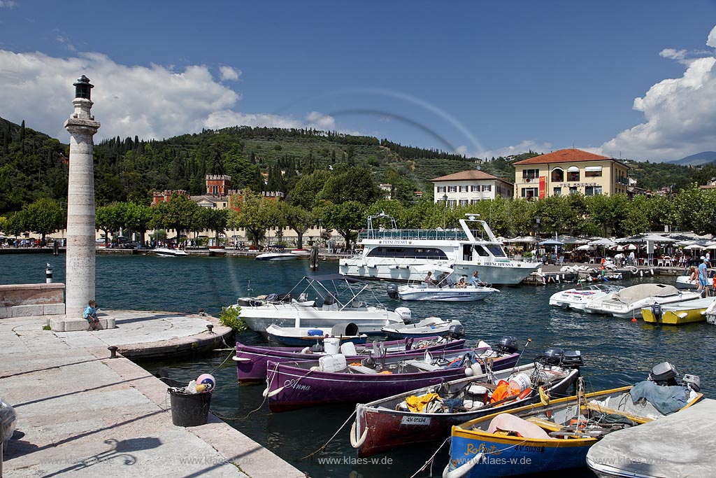 Garda Blick von Hafenmole mit bunten Fischerbooten, Motoryacht und Leuchtmast zur Villa Albertini; Garda view from mole over port with colourful fishing boats, motoryacht and lightmast to Villa Albertini