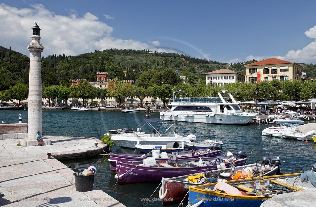 Garda Blick von Hafenmole mit bunten Fischerbooten, Motoryacht und Leuchtmast zur Villa Albertini; Garda view from mole over port with colourful fishing boats, motoryacht and lightmast to Villa Albertini