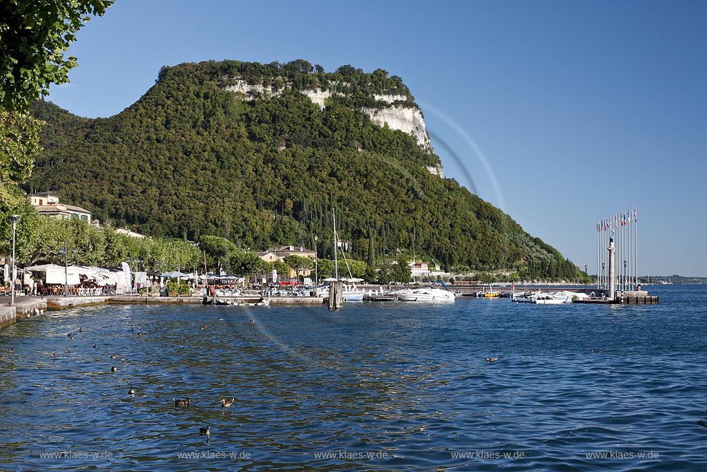 Garda Blick von der Promenade mit Gardasee zum Rocca di Garda bei wolkenlosem Himmel in stimmungsvollem warmem Sonnenlicht; Garda view from promenade with Lake garda to the mountain Rocca di Garda cloudless atmospheric late afernoon sunlight