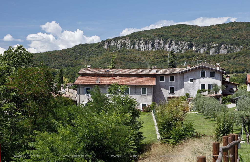 Garda Bauenhauf ueber dem Tal der Muehlen in Sommerlandschaft mit Berglandschaft im Hintergrund; Garda farm over the over valley of mills, landscape with mountain; Garda Val dei Mulini