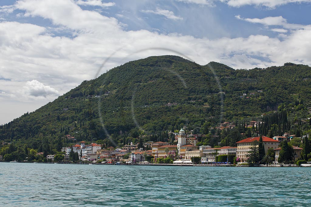 Gardone Riviera, Panoramablick vom Gardasee aus auf den Ort, Seeseite mit Seepromenade und den modernen Hotels dahinter der Monta San Bartolomeo, Wolkenstimmung; Gardone Rivera, view from lake Garda to the town with promenade in front of elegant late 19th century hotels, in backgrount mountain Monte St. Bartolomeo, atmospheric clouds; Gardone Riviera il lungolago davanti agli eleganti hotel di fine ottocento