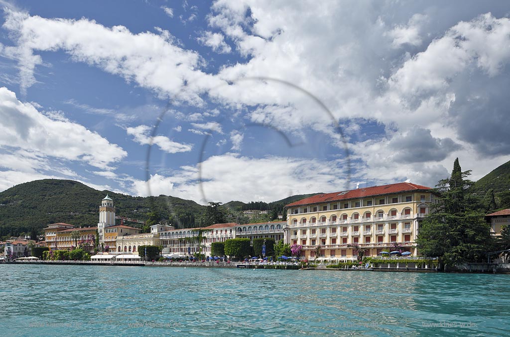 Gardone Riviera, Panoramablick vom Gardasee aus auf den Ort, Seeseite mit Seepromenade und den modernen Hotels dahinter der Monta San Bartolomeo, Wolkenstimmung; Gardone Rivera, view from lake Garda to the town with promenade in front of elegant late 19th century hotels, in backgrount mountain Monte St. Bartolomeo, atmospheric clouds; Gardone Riviera il lungolago davanti agli eleganti hotel di fine ottocento