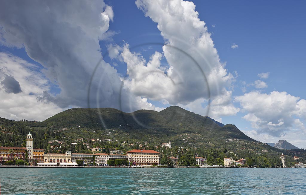 Gardone Riviera, Panoramablick vom Gardasee aus auf den Ort, Seeseite mit Seepromenade und den modernen Hotels, rechts der Turm von San Marco, ehemaliges Bootshaus der Villa Alba, la Torre di San Marco, Wolkenstimmung; Gardone Rivera, view from lake Garda to the town with promenade in front of elegant late 19th century hotels, right side the St. Mark's tower, once the boathouse at Villa Alba, atmospheric clouds; Gardone Riviera il lungolago davanti agli eleganti hotel di fine ottocento et la torre di San Marco, gia darsenadi Villa Alba