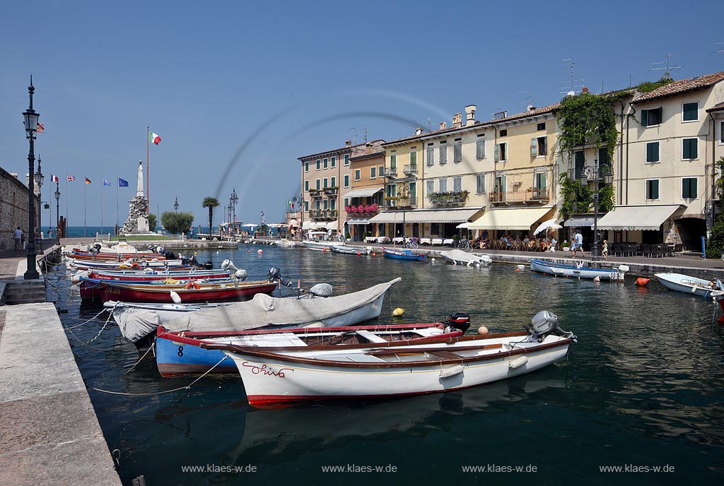 Lazise, Blick ueber den Hafen Richtung Gardasee mit bunten Fischerbooten und Haeusern sowie dem Denkmal fuer Kriegsgefallene; Lazise, view over the port with colourfull fishing boats, houses and war victim memoirial 