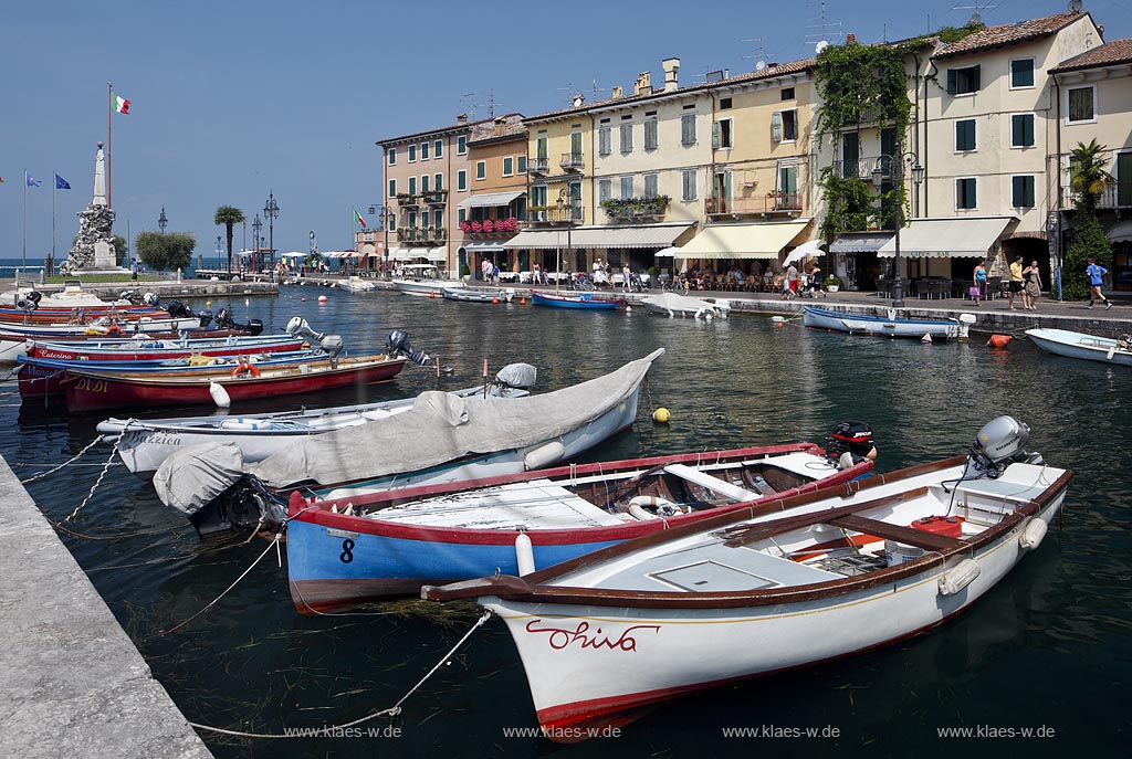 Lazise, Blick ueber den Hafen Richtung Gardasee mit bunten Fischerbooten und Haeusern sowie dem Denkmal fuer Kriegsgefallene; Lazise, view over the port with colourfull fishing boats, houses and war victim memoirial 