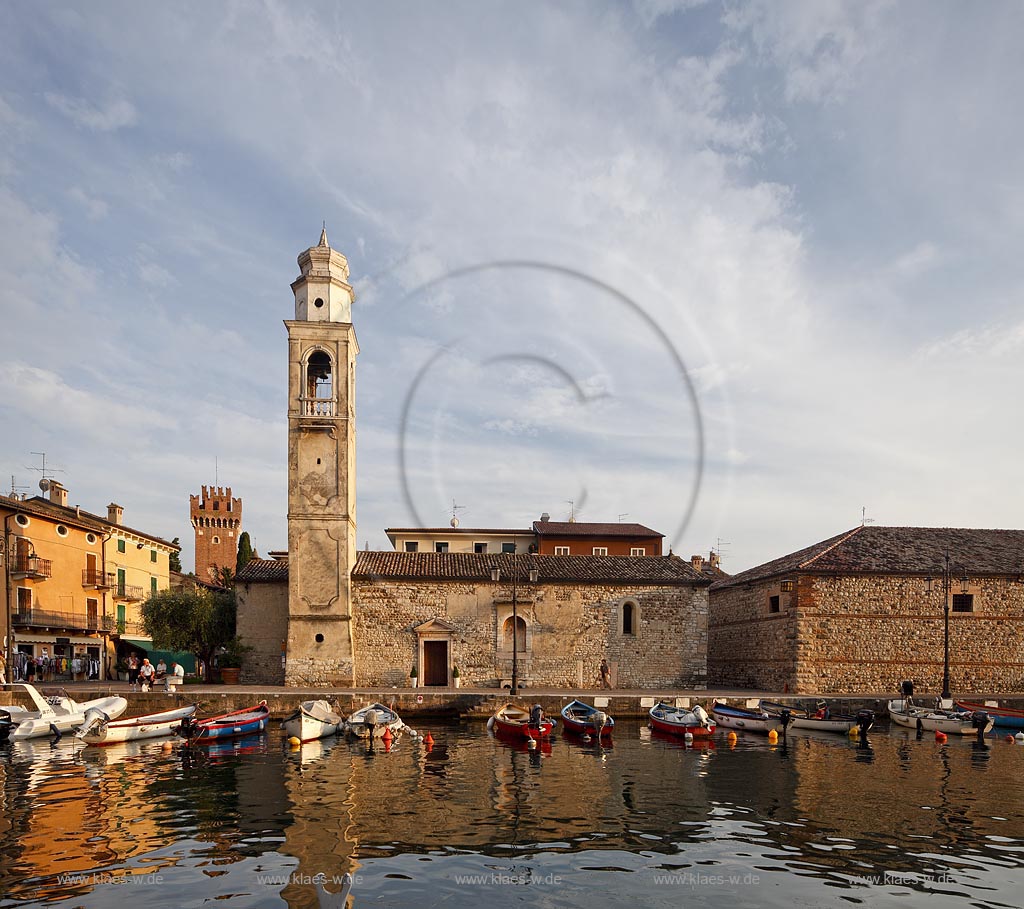 Lazise Blick ueber den Hafen mit Fischerbooten zur kleinen Kirche St. Nicolo im stimmungsvollen warmen Abendlicht der untergehenden Sonne; Laszise view over the port with fishing boats to the church of San Nicolo in atmospheric evening sunset light; Lazise il portoicciolo, la chiesa romanica di San Nicolo 