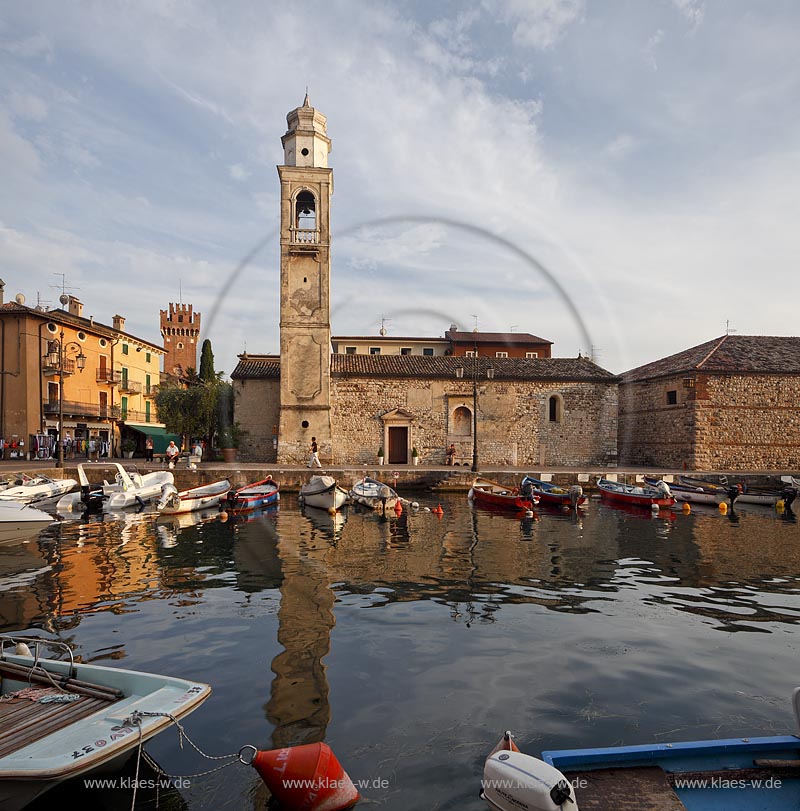 Lazise Blick ueber den Hafen mit Fischerbooten zur kleinen Kirche St. Nicolo im stimmungsvollen warmen Abendlicht der untergehenden Sonne; Laszise view over the port with fishing boats to the church of San Nicolo in atmospheric evening sunset light; Lazise il portoicciolo, la chiesa romanica di San Nicolo 