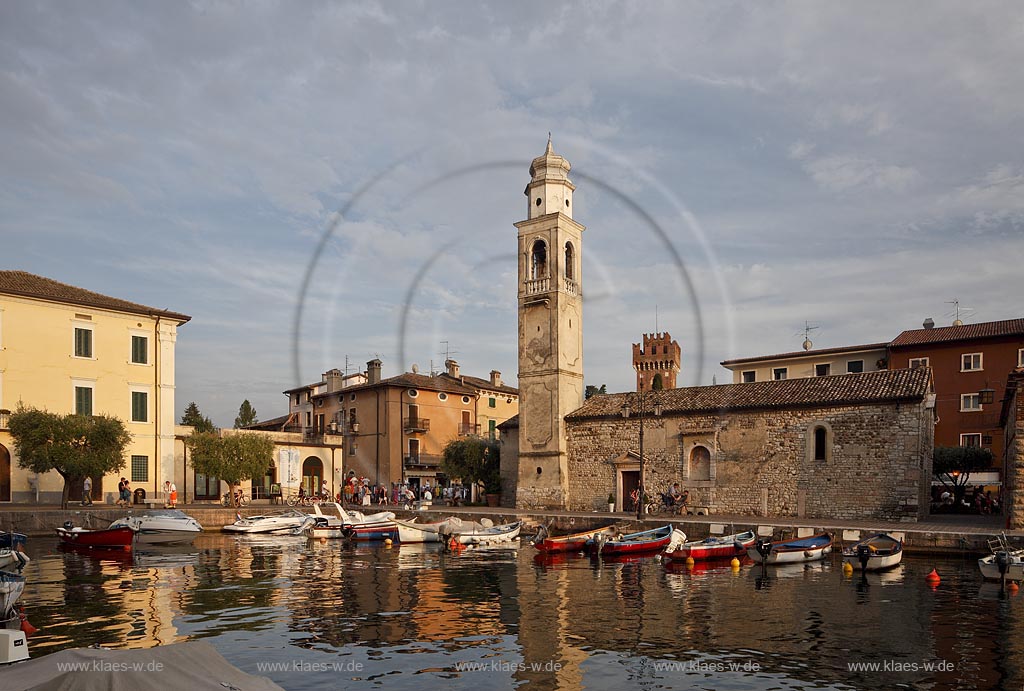 Lazise Blick ueber den Hafen mit Fischerbooten zur kleinen Kirche St. Nicolo im stimmungsvollen warmen Abendlicht der untergehenden Sonne; Laszise view over the port with fishing boats to the church of San Nicolo in atmospheric evening sunset light; Lazise il portoicciolo, la chiesa romanica di San Nicolo 