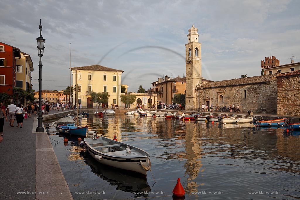 Lazise Blick ueber den Hafen mit Fischerbooten zur kleinen Kirche St. Nicolo im stimmungsvollen warmen Abendlicht der untergehenden Sonne; Laszise view over the port with fishing boats to the church of San Nicolo in atmospheric evening sunset light; Lazise il portoicciolo, la chiesa romanica di San Nicolo 