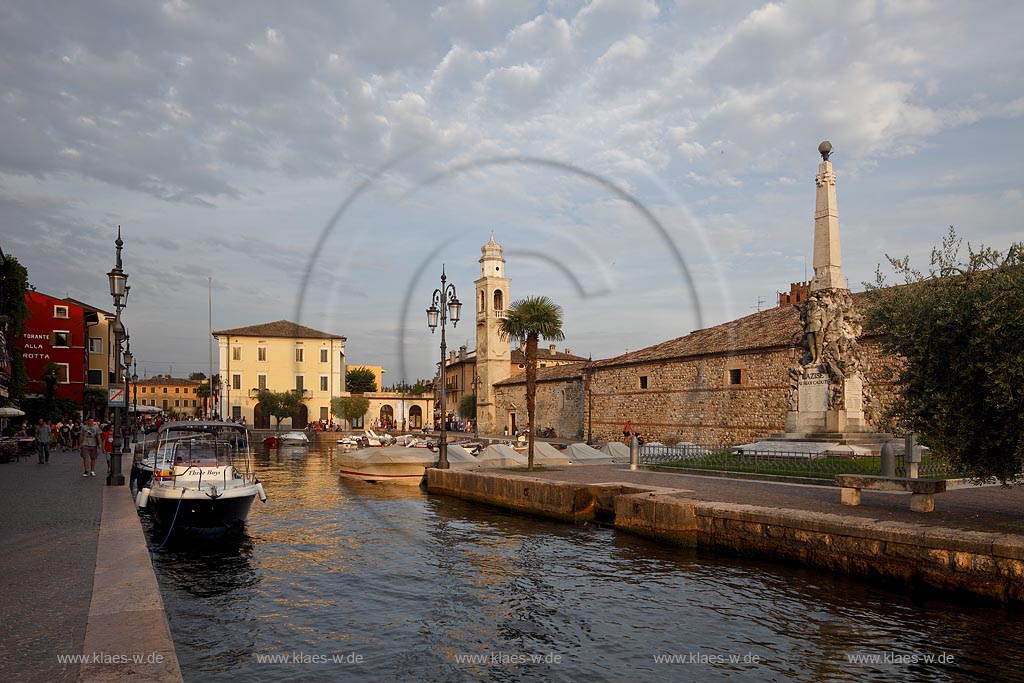Lazise Blick ueber den Hafen mit Fischerbooten zur kleinen Kirche St. Nicolo im stimmungsvollen warmen Abendlicht der untergehenden Sonne; Laszise view over the port with fishing boats to the church of San Nicolo in atmospheric evening sunset light; Lazise il portoicciolo, la chiesa romanica di San Nicolo 