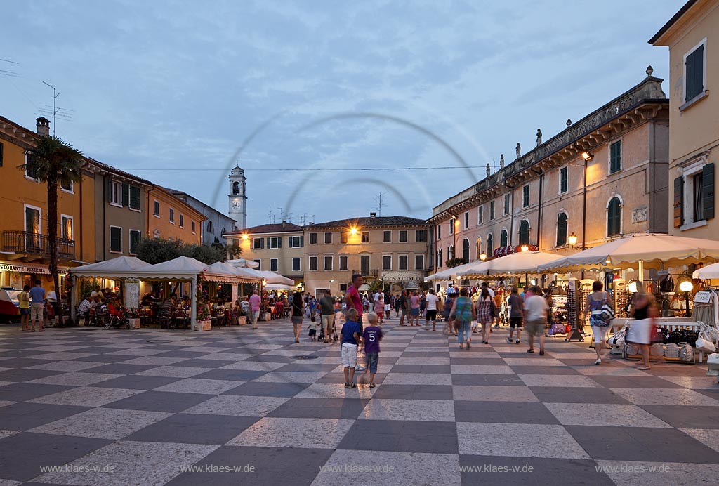 Lazise Piazza Vittorio Emanuele mit seinem Schachbettmuster; Hausern und Passanten zur blauen Stunde; Lazise Piazza Vittorio Emanuele cobbled like a chess board during blue hour