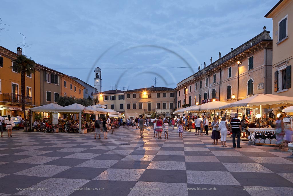 Lazise Piazza Vittorio Emanuele mit seinem Schachbettmuster; Hausern und Passanten zur blauen Stunde; Lazise Piazza Vittorio Emanuele cobbled like a chess board during blue hour