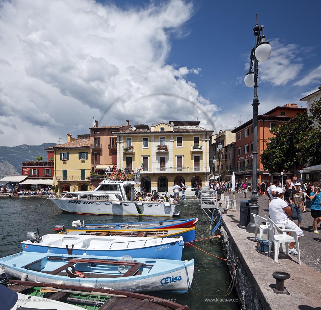 Malcesina, Blick ueber den Hafen mit buntern Fischerbooten, Motoryacht und bunten Haeusern in extremer Wolkenstimmung; Malcesine view over port with colourful fishing boats, motoryacht and pettily painted houses, atmospheric clouds