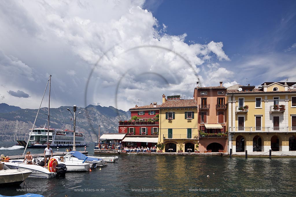 Malcesina, Blick ueber den Hafen mit Motorbooten und bunten Haeusern in extremer Wolkenstimmung, Faehrschiff Tonale auf dem gardasee; Malcesine view over port with motorsboat, motoryacht and pettily painted houses, atmospheric clouds, ferryboat Tonale on lake garda