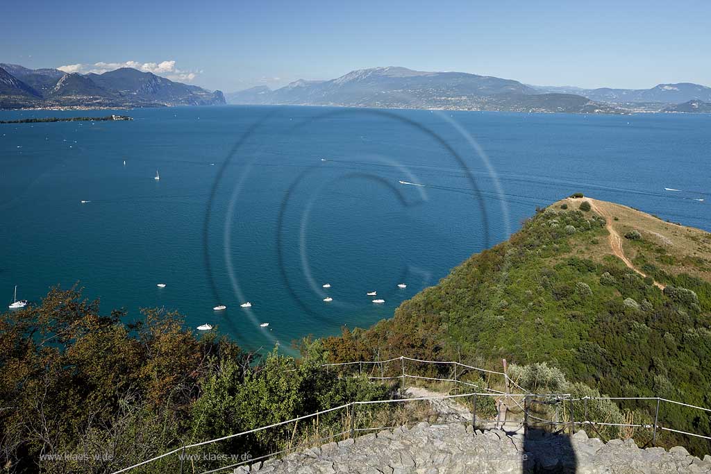 Manerba del Garda, Blick von Rocca di Manerba ueber den Gardasse in noerdliche Richtung mit Bergkette des Monte Baldo, Motorboote auf dem See fahrend und liegend; Manerba del Garda, a clear view from Rocca di Manerba onto Lake Garda, to the northern line of sight with Monta Baldo in the background, motorboats on the lake.