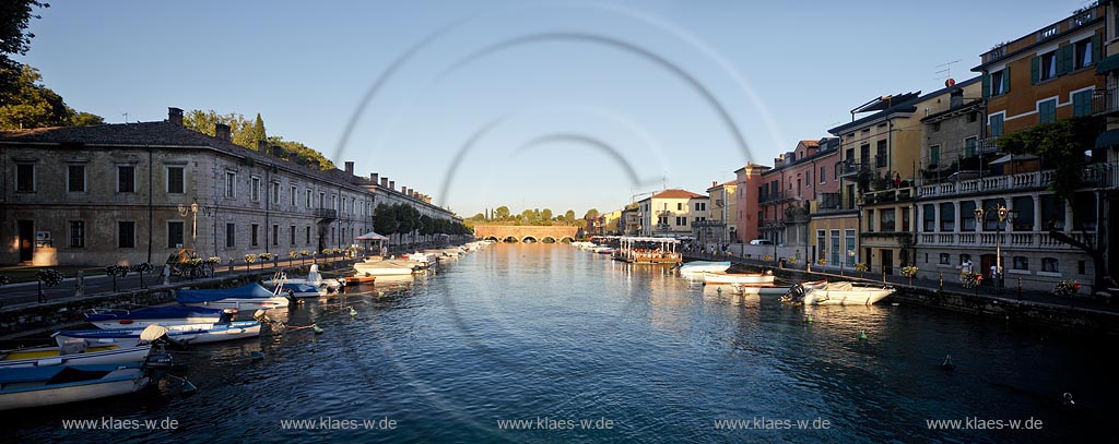 Peschiera, Abenstimmung mit Panoramablick ueber den Canale di Mezzo mit Fischerbooten zur Voltoni Bruecke im stimmungsvollen Abendlicht der untergehenden Sonne; Peschiera panorama view over Canale di Mezzo with fishing boats to the Voltoni bridge in background in evening sunset light