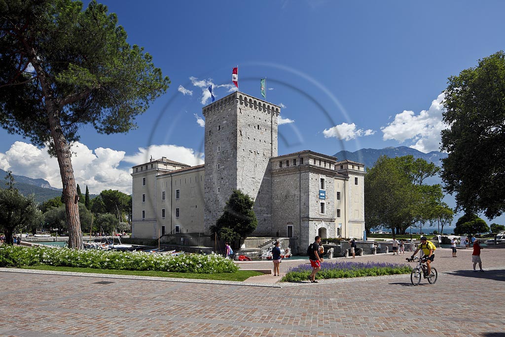 Riva del Garda, Stadtburg Rocca, Wasserburg aus dem 12.Jjahrhundert mit Fussgaengern, Passanten und Radfahrern; Riva del garda, the Rocca, a moated castle of 12th century with passersby and bikers