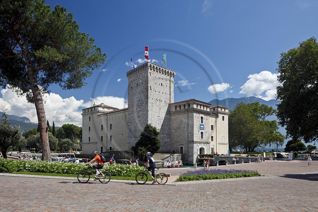 Riva del Garda, Stadtburg Rocca, Wasserburg aus dem 12.Jjahrhundert mit Fussgaengern, Passanten und Radfahrern; Riva del garda, the Rocca, a moated castle of 12th century with passersby and bikers