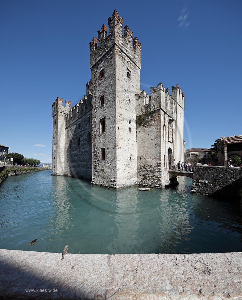Sirmione, Nahaufnahme der Scaliger Burg, im Vordergrund eine Mauerbruestung mit Haussperling der die Szenerie neugierig zu betrachten scheint; Sirmione, closeup of the Scaliger castle with a house sperrow in the front of picture