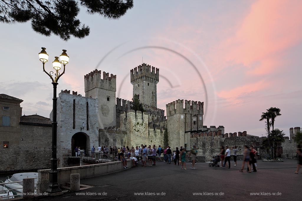 Sirmione, Blick zur Scaliger Burg im Licht der untergehenden Abendsonne, rote Wolken, blaue Stunde mit Illumination; Sirmione, view  to the Scaliger castle during sunset light with red lighted clouds during blue hour, illuminated