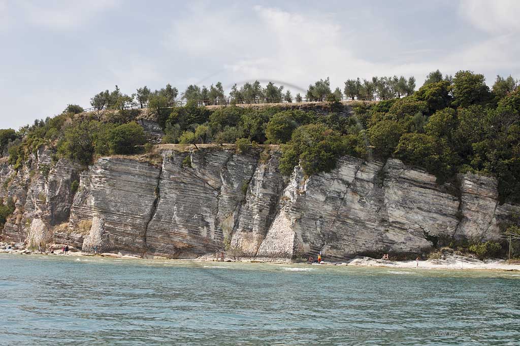 Sirmione, Blick vom Gardasee auf Steilklippen mit schmalem Badestrand und Badeenden; Sirmione, view from Lake Garda onto cliff with beach.