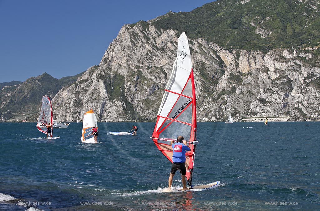 Torbole sul Garda, Circolo Velo Torbole, Blick ueber den Gardasee mit Surfern und  Bergkulisse im Hintergrund, tuerkis schimmernde Wasseroberflaeche, windig; Torbole sul Garda, Circolo Velo Torbole, view over the Lake Garda with wind surfers and mountains in the background, windy