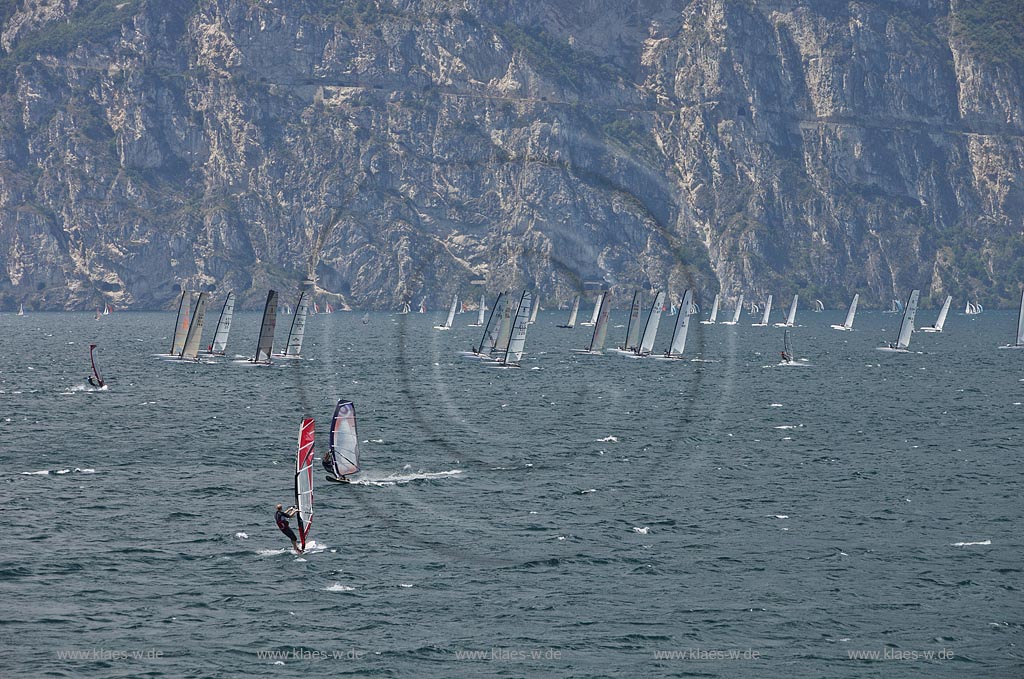 Torbole sul Garda, Surfern auf dem Gardasee bei stuermischem Wind, im Hintergrund Segelkatamaran Regatta vor schroffen Felswaenden; Torbole sul Garda, Lake Garda with wind surfers, windy, in the background a sail catamaran regata and rocks mass