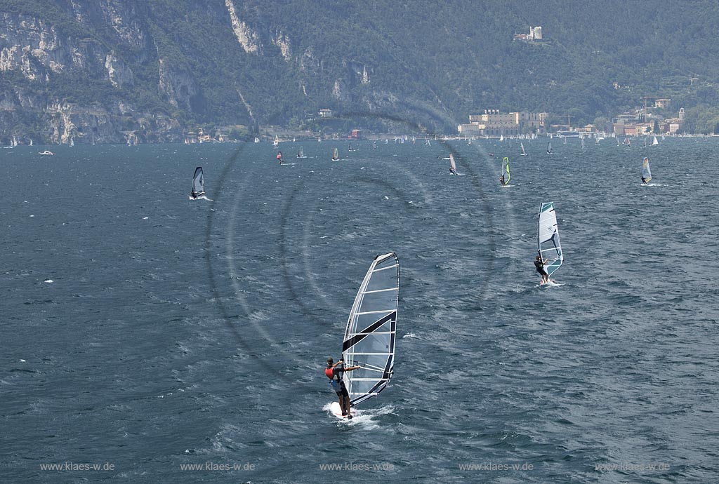 Torbole sul Garda, Blick ueber den Gardasee mit Surfern und Riva del Garda mit dem Bastion, der von den Venezianern erbaute Hauptturm, stuermisch; Torbole sul Garda, view over the Lake Garda with wind surfers and Riave del Garda with the Bastione, a watchtower, built by the Venetianss in the background, impressive clouds atmosphere, stormy wind
