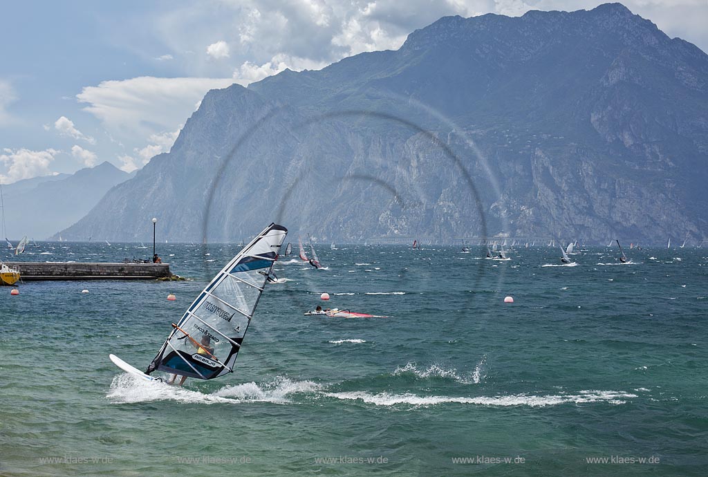 Torbole sul Garda, Blick ueber den Gardasee mit Surfern und  Bergpanorama im Hinterkulisse, tuerkis schimmernde Wasseroberflaeche, stuermisch; Torbole sul Garda, view over the Lake Garda with wind surfers and mountains in the background, impressive clouds atmosphere, stormy wind