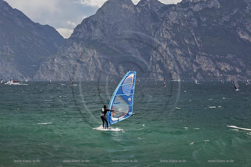 Torbole sul Garda, Blick ueber den Gardasee mit Surfern und  Bergpanorama im Hinterkulisse, tuerkis schimmernde Wasseroberflaeche, stuermisch; Torbole sul Garda, view over the Lake Garda with wind surfers and mountains in the background, impressive clouds atmosphere, stormy wind