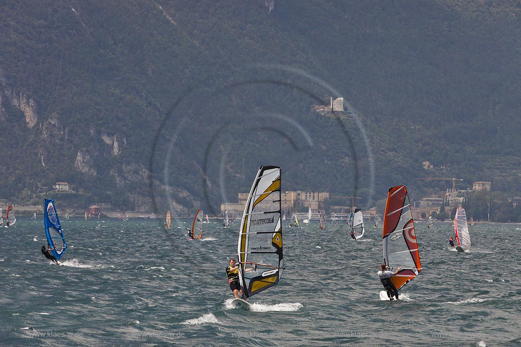 Torbole sul Garda, Blick ueber den Gardasee mit Surfern und Riva del Garda mit dem Bastion, der von den Venezianern erbaute Hauptturm, stuermisch; Torbole sul Garda, view over the Lake Garda with wind surfers and Riave del Garda with the Bastione, a watchtower, built by the Venetianss in the background, impressive clouds atmosphere, stormy wind