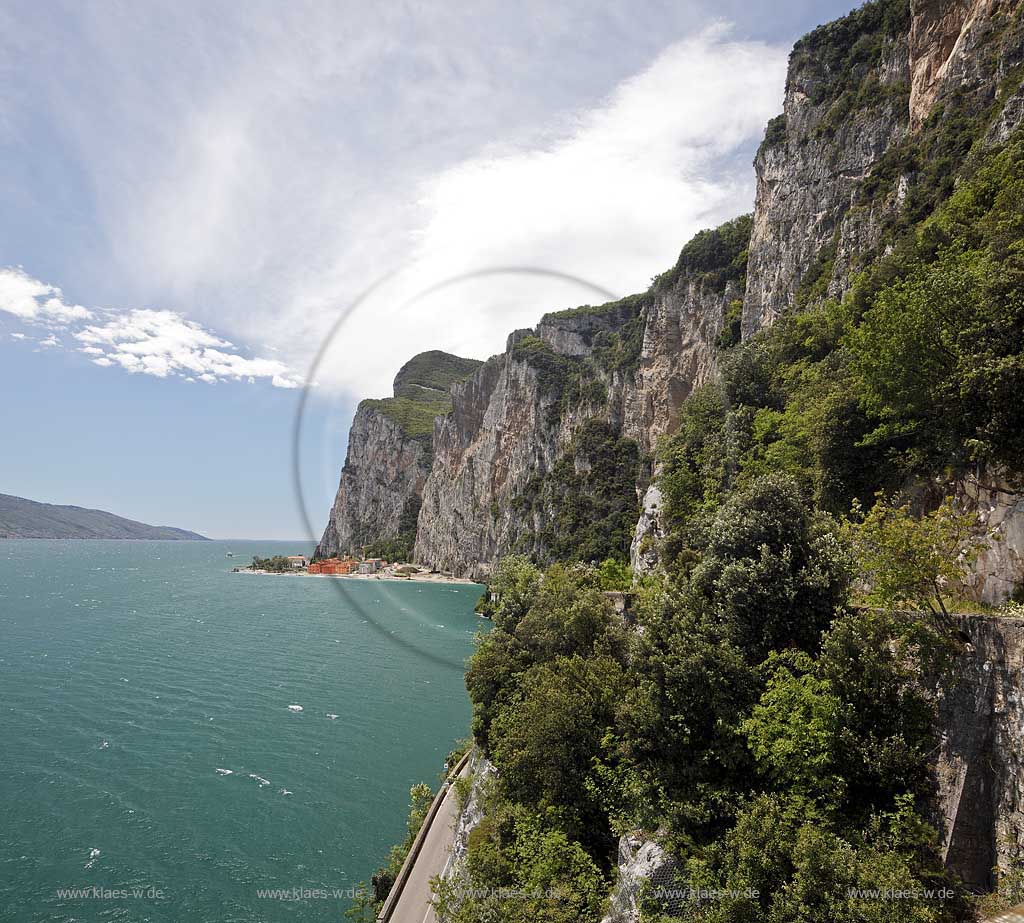 Tremosine, Blick ueber Gardaseestrasse mit Autos in mediteraner vegetation, Zypresssen mit Gadasee und schroffen Felswaenden, im Hintergind Campione del Garda; Tremosine, view over lake garda street with cars, cypress trees ,lake Garda, rocks and the village Campione del garda