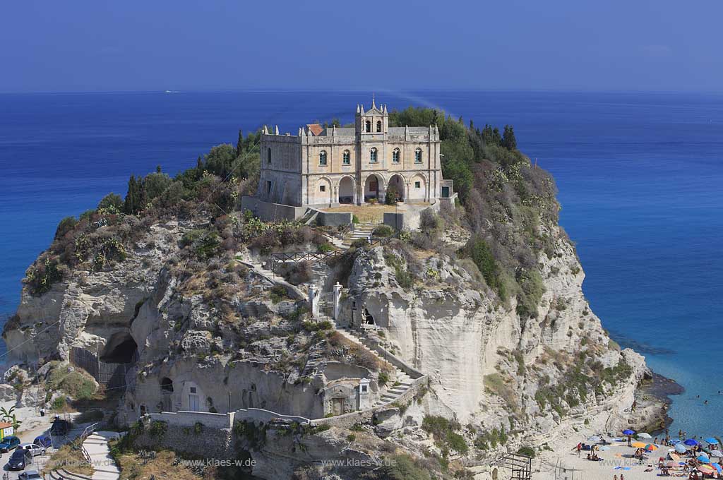 Blick auf die auf einem Felsen gelegene Wallfahrtskirche Chiesa Santa Maria dell'Isola in Tropea, Kalabrien, Italien mit Sicht auf das Meer und Menschen, Touristen am Strand