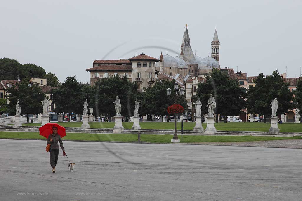 Padua Prato della valle mit Kathedrale, Basilika San Antonius an einem regnerischen Tag mit einer Frau, Italienerin mit einem Hund an Leine und offener leutend roter Regenschirm; Prato della valle with Cathedrale Saint Anthonys Basilica at a rainy day with one women with a dog and open umbrella; Padova 