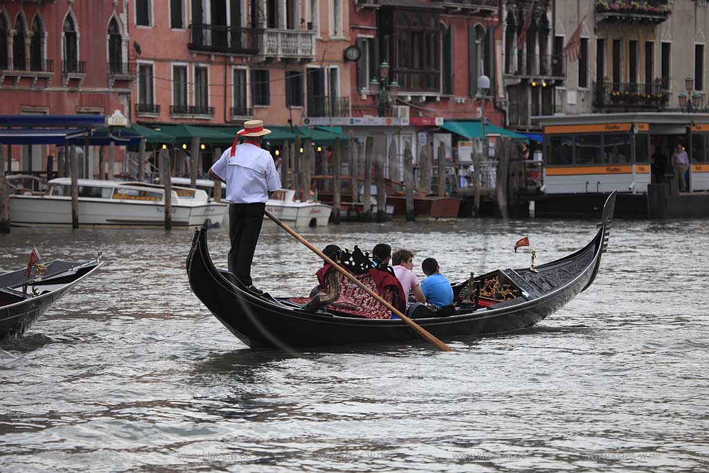 Venedig, Rialto, Canal Grande, Gondel mit Gondoliere Abbildung von hinten weisses Hemd und Hut, vier Personen in Gondel sitzend; Venice Rialto Canal Grande gondola with gondolier with hut four people sitting in the gondola backview