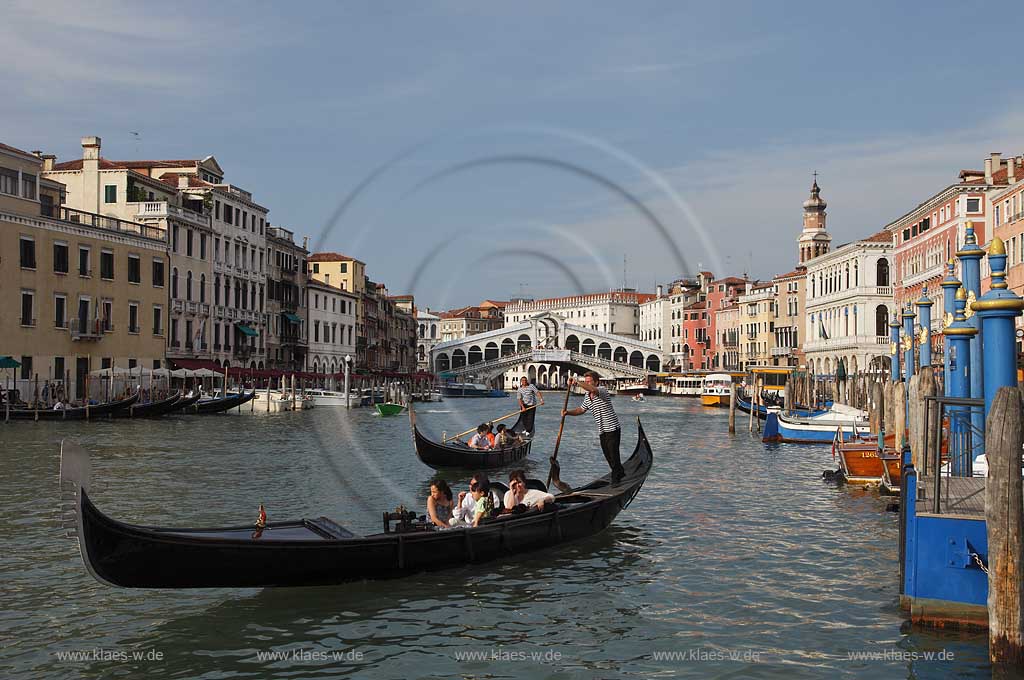 Venedig, Rialto, Blick von Riva del Carbon auf Kanal Grande mit der Rialtobruecke Ponte di Rialto, Kirchturm Campanile der Kirche Chiesea dei San Bartolomeo, Gondeln mit Gondoliere mit T Shirt quergestreift und mehreren Personen in Gondeln sitzend, eine Gondel Vordergund betonend ; Venice Rialto view from Riva del Carbon to Canal Grande with Rialto bridge, gondola and gondolier in raye transversalement t-shirt, several person sitting in gondola, one gondola near in front of picture, tower of church San Bartolomeo