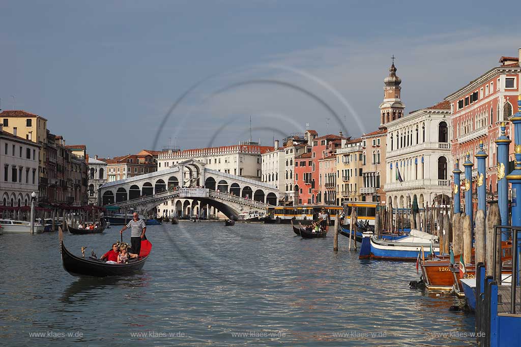 Venedig, Rialto, Blick von Riva del Carbon auf Kanal Grande mit der Rialtobruecke Ponte di Rialto, Kirchturm Campanile der Kirche Chiesea dei San Bartolomeo, Gondel mit Gondoliere mit T Shirt quergestreift und ein Paar in mittlerem Alter in Gondel sitzend; Venice Rialto view from Riva del Carbon to Canal Grande with Rialto bridge, gondola and gondolier in raye transversalement t-shirt, midlife couple middle age couple sitting in gondola, tower of church San Bartolomeo