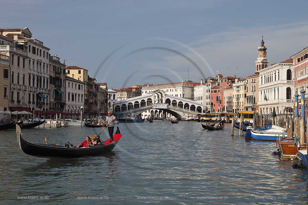 Venedig, Rialto, Blick von Riva del Carbon auf Kanal Grande mit der Rialtobruecke Ponte di Rialto, Kirchturm Campanile der Kirche Chiesea dei San Bartolomeo, Gondel mit Gondoliere mit T Shirt quergestreift und ein Paar in mittlerem Alter in Gondel sitzend; Venice Rialto view from Riva del Carbon to Canal Grande with Rialto bridge, gondola and gondolier in raye transversalement t-shirt, midlife couple middle age couple sitting in gondola, tower of church San Bartolomeo
