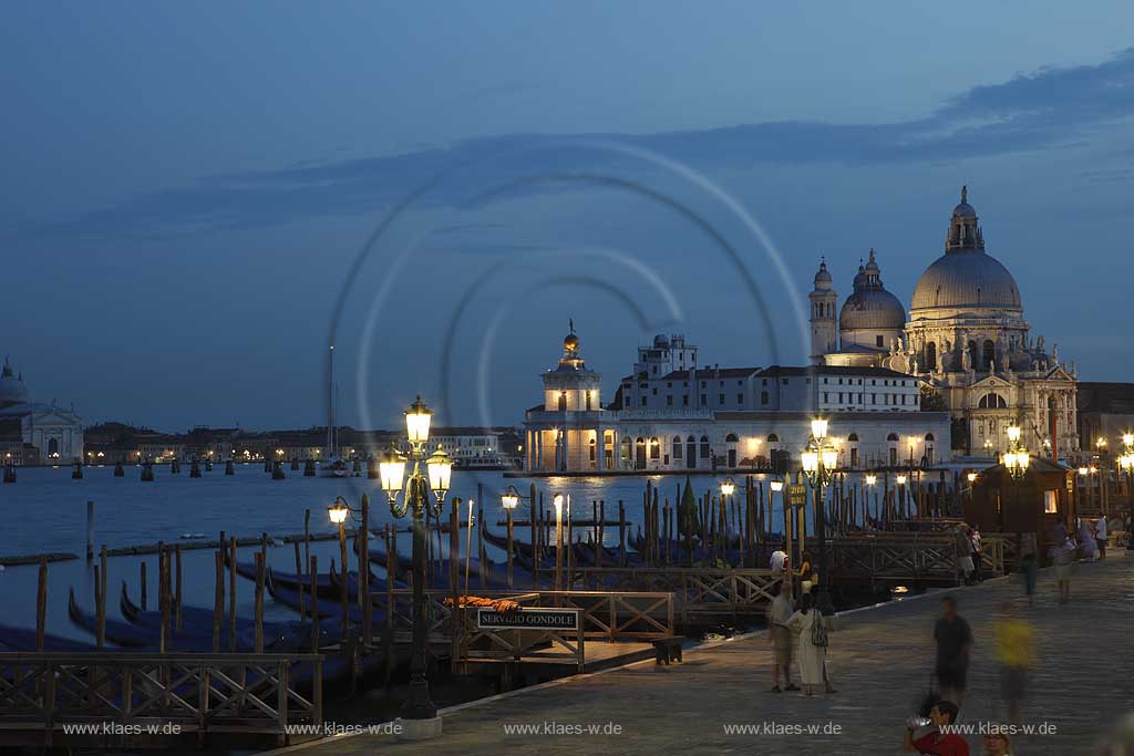 Venedig Blick von Riva degli Schiavoni ueber Mole mit Gondeln und Kanal di San Marco zur Basilika di Santa Maria della Salute zur Blauen Stunde mit Strassenlaternen beleuchtet, illuminiert; Venice view from Riva degli Schiavoni with mole, gondola and canal di San Marco to basilica San Maria della Salute in nightlight, evening light blue hour with illumination and glowing lantern