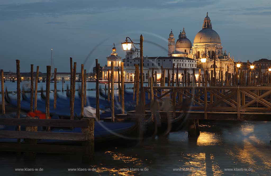 Venedig Blick von Riva degli Schiavoni ueber Mole mit Gondeln und Kanal di San Marco zur Basilika di Santa Maria della Salute zur Blauen Stunde mit Strassenlaternen beleuchtet, illuminiert; Venice view from Riva degli Schiavoni with mole, gondola and canal di San Marco to basilica San Maria della Salute in nightlight, evening light blue hour with illumination and glowing lantern