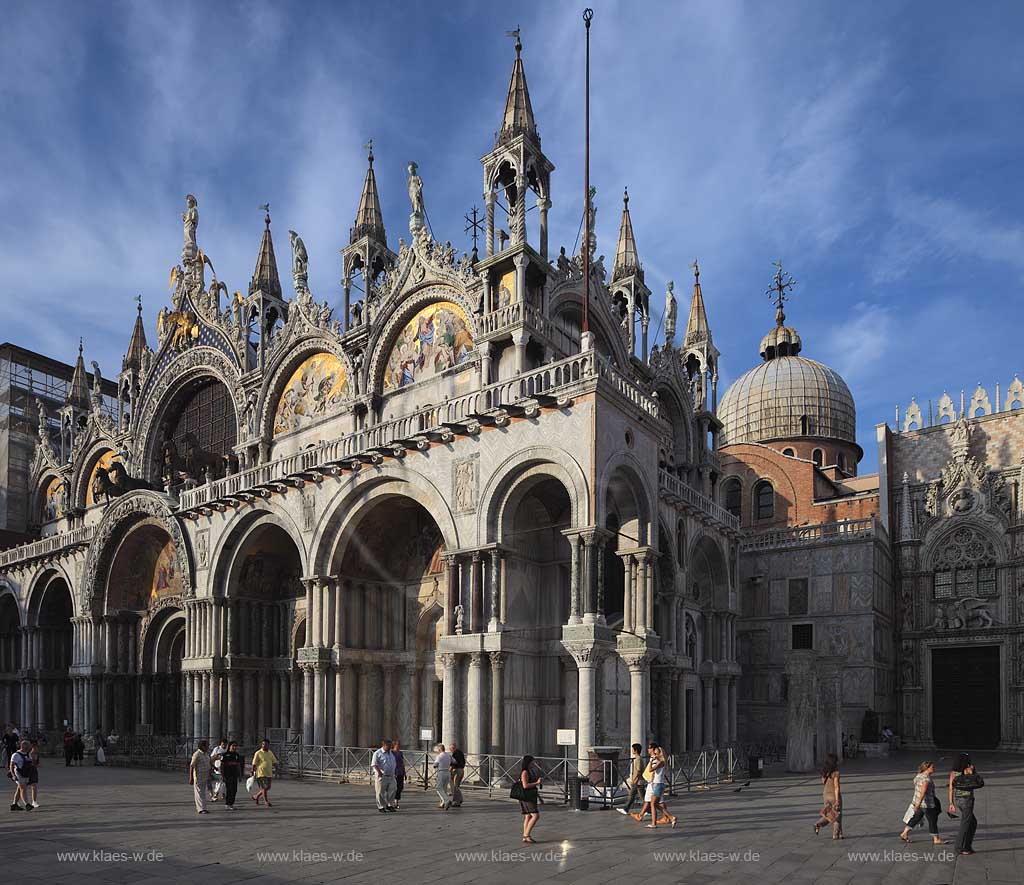 Venedig Markusplatz Blick auf die Hauptfassade mit Hauptportal der Markuskirche mit Menschen, Touristen im saeten Nachmittagslicht, stimmungsvoll; Venice Piazza San Marco with view to facade of Basilica di San Marco with the main portal and people, tourists on the square in impressive evening sunlight