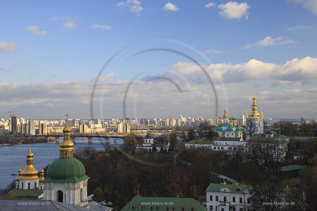 Blick mit Kreuzerhoehungskirche des Heiligen Kiewer Mariae Entschlafens Hoehlenkloster Svjato-uspens'ka Kyjevo Pecers'ka lavra . Petscherska Lawra, untere Lawra im Hintergrund die Hochhaeuser des rechten Dnepr Ufers mit der Paton Brcke . The historic Kiyevo-Pecherska Lavra (caves monastery of Kiev) stretches along the Dnipro in the middle of Pechersk district - one of the oldest parts of Kyiv. The whole area of the monastery is 28 hectare big, quite hilly and numerous caves run through the underground - hence the name. Since 1051, monks lived inside the caves, which also marked the foundation of the monastery. 