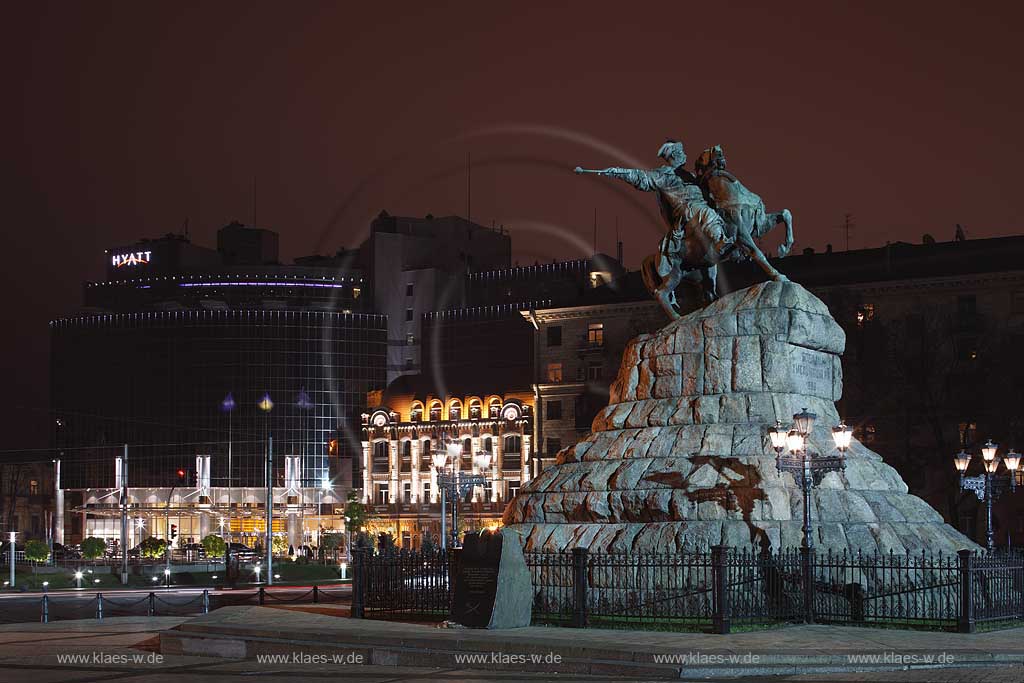 Kiew Sophienplatz mit dem modernen Neubau des Hyatt Hotel mit Glasfassade im Hintergund und dem Bohdan Chmeinyz'kyi Denkmal einem Reiterstandbild auf einem Sockel aus roten Granitbloecken des Bildhauers Mychajlo Mikeshin  im Vordergrund in abendlicher naechtlicher nchtlicher Beleuchtung. Bohdan Khmelnytsky square with Bohdan Chmeinyz'kyi monument and Hyatt hotel at evening light.