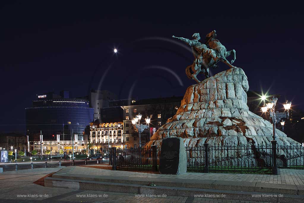 Kiew Sophienplatz mit dem modernen Neubau des Hyatt Hotel mit Glasfassade im Hintergund und dem Bohdan Chmeinyz'kyi Denkmal einem Reiterstandbild auf einem Sockel aus roten Granitbloecken des Bildhauers Mychajlo Mikeshin  im Vordergrund in abendlicher naechtlicher nchtlicher Beleuchtung. Bohdan Khmelnytsky square with Bohdan Chmeinyz'kyi monument and Hyatt hotel at evening light.