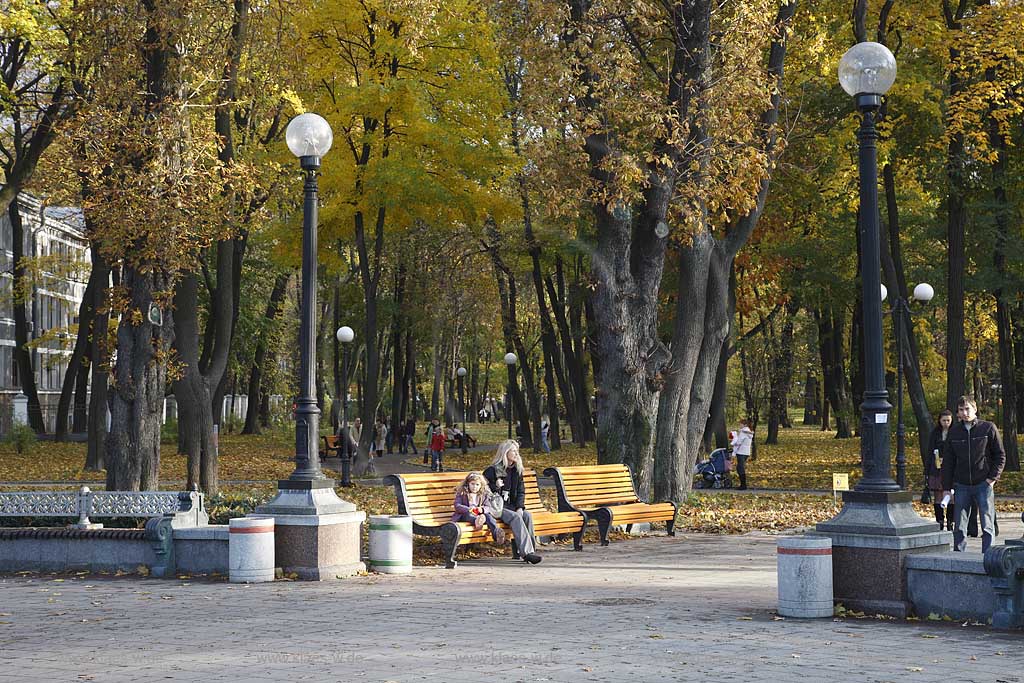 Kiew Blick zum Mariinski Marijiins'kyi Park mit Parkbank und sitzenden Menschen. Mariyinskiy Garden. This city garden was formerly known as the Tsarskiy Garden. This is a formal garden laid out in front of the Mariyinskiy Palace with fountains and statues