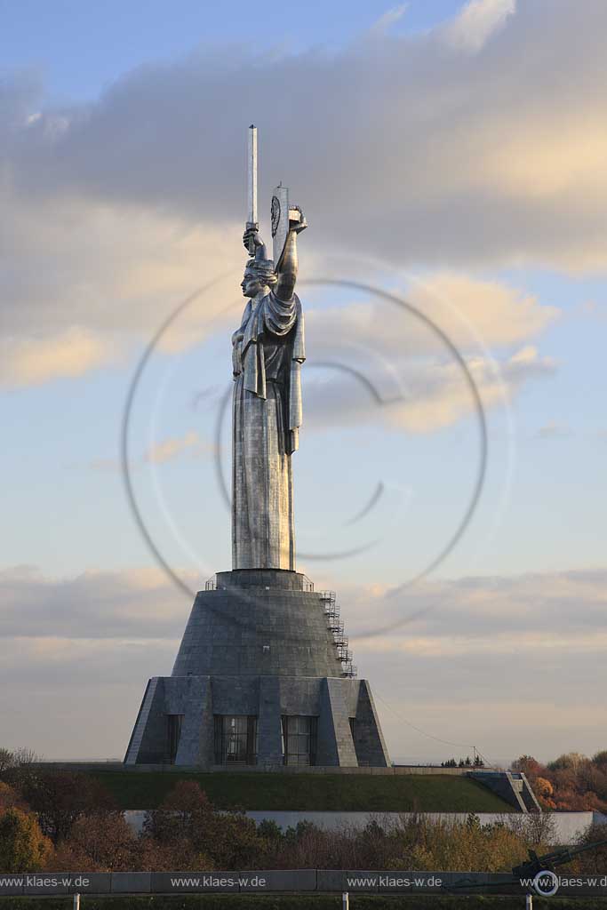 Kiew Statue der Mutter Heimat Rodina mat' mit Schwert und Schild im Park des Ruhmes  aus Metall 108 m hoch einschliesslich Sockel aufgenommen an einem klaren Herbsttag bei tiefstehendem Sonnenlicht stimmungsvoll blauer Himmel mit Wolken . National Museum about the History of the Great Patriotic War against Nazi-Germany with the large monument "Rodina Mat'", lit. 'Mother Home country'. The monument itself is more than 100 m high and reminds the visitor of the devastating but glorious fight against Hitler.