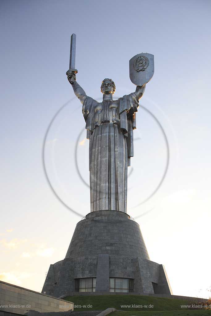 Kiew Statue der Mutter Heimat Rodina mat' mit Schwert und Schild im Park des Ruhmes  aus Metall 108 m hoch einschliesslich Sockel aufgenommen an einem klaren Herbsttag bei tiefstehendem Sonnenlicht stimmungsvoll blauer Himmel mit Wolken . National Museum about the History of the Great Patriotic War against Nazi-Germany with the large monument "Rodina Mat'", lit. 'Mother Home country'. The monument itself is more than 100 m high and reminds the visitor of the devastating but glorious fight against Hitler.