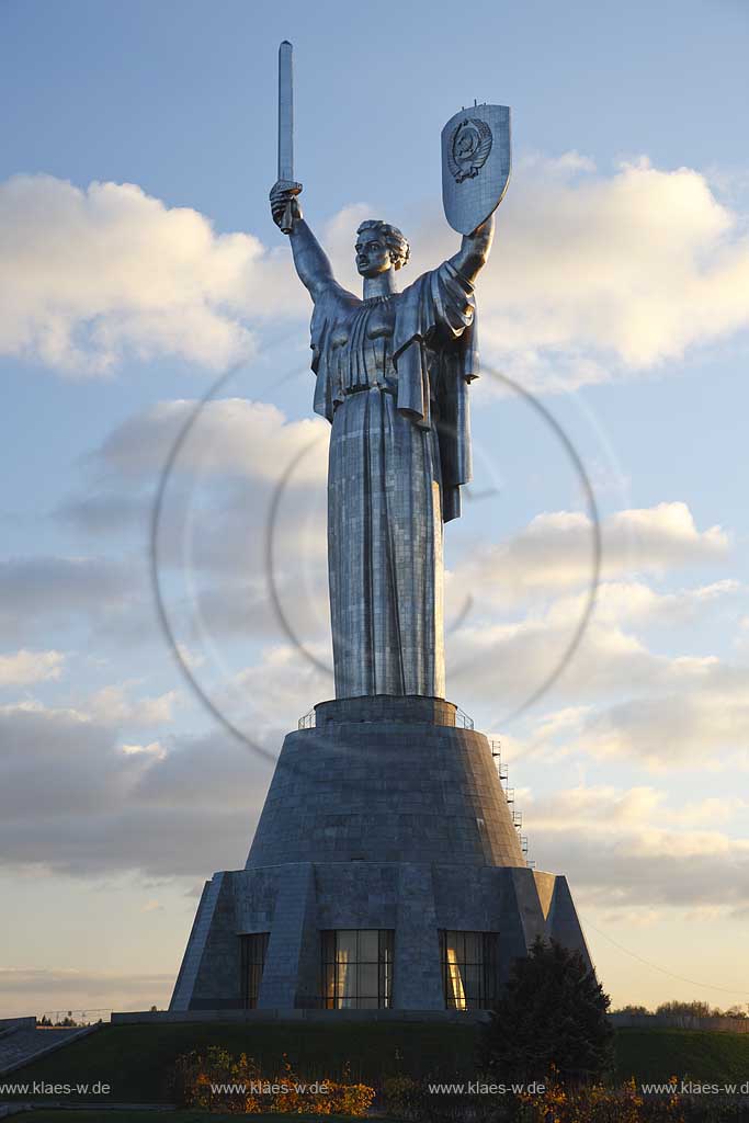 Kiew Statue der Mutter Heimat Rodina mat' mit Schwert und Schild im Park des Ruhmes  aus Metall 108 m hoch einschliesslich Sockel aufgenommen an einem klaren Herbsttag bei tiefstehendem Sonnenlicht stimmungsvoll blauer Himmel mit Wolken . National Museum about the History of the Great Patriotic War against Nazi-Germany with the large monument "Rodina Mat'", lit. 'Mother Home country'. The monument itself is more than 100 m high and reminds the visitor of the devastating but glorious fight against Hitler.